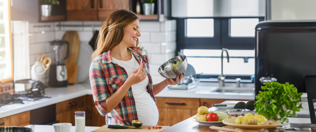 Schwangere Frau isst Salat.